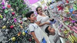 Hosana Nunes de Freitas e os filhos André (de pé) e Davi escolhem produtos de Natal em loja estabelecida na Rua 3, Centro